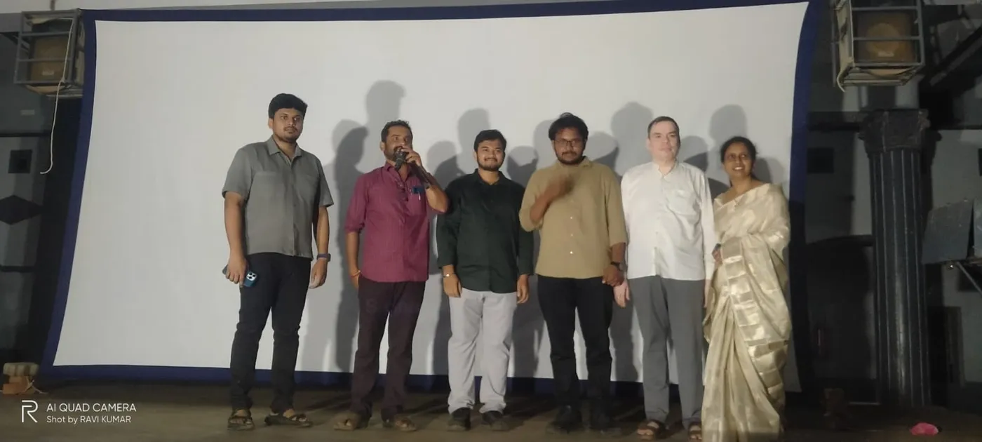On stage at the event in front of the projector screen, with the school management